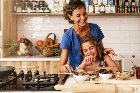 Little girl cooking with mother in kitchen